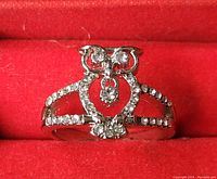 Close-up photo of sterling silver owl ring showing white stones on owl shape and band inside red jewelry box.