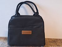 Front view of the black Lidenkors thermal lunch bag showing the brand patch and dual handles
