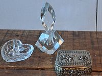 Photo showing all three items: the heart-shaped glass ring holder, the faceted glass perfume bottle, and the vintage metal jewelry box with detailed lid design