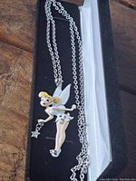 Full view of Tinkerbell pendant necklace in black box on wooden surface.