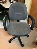 Front view of office chair showing gray fabric upholstery, armrests, and base