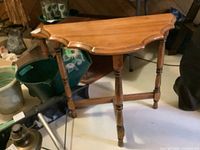 Demilune table showing the half-moon-shaped wood top with scalloped edges and three turned legs.