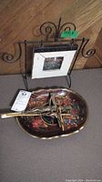 Steel and wood photo frame with scroll design, wooden handpainted floral tray, and two brass tone crucifixes on a table.