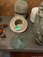 Image showing the Celtic style planter with intricate knotwork, metal leaf with frog detail, and composite head sculpture arranged on a table surface.