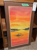 Full view of framed sunset painting with label indicating 23 x 12 art and 27 x 16 frame.