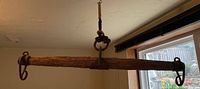 Full view of 33 inch wooden yoke suspended from ceiling with braided rope and iron hooks on each end