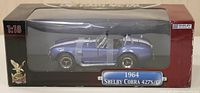 Model car boxed in original packaging with clear plastic window showcasing the detailed blue and white 1964 Shelby Cobra 427S/C model.