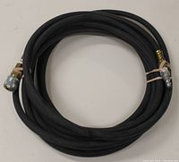 Coiled black air hose with 'M' style male and female connectors on each end, placed on a plain surface.