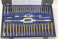 Photo of the inside of the metal case showing the organized array of taps and dies with two tap handles and die holders placed in foam insert. Tools have a gold titanium coating and hexagonal dies.