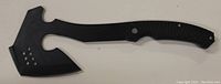 Photo of black tactical axe showing one side with broad cutting edge and ergonomic handle with ridges for grip