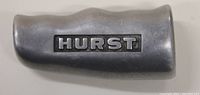 Side view of metal shifter handle showing the HURST logo embossed and recessed with black paint filling.