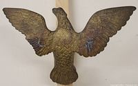Front view of large brass eagle sculpture with wings spread wide showing detailed feather pattern.