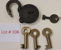 Photo showing old iron padlock open with three brass skeleton keys and one black key tagged separately.