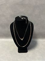 Full display of two necklaces on black bust stand and bracelet clasp draped over the top.