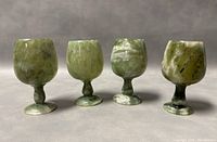 Four green jade wine goblets arranged standing upright showing size and shape.
