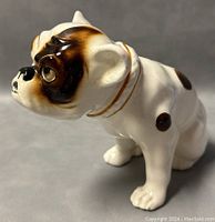 Side view of the glossy white porcelain bulldog figurine with brown and black patches, showing detailed facial features and collar.