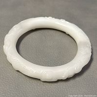Photo of carved white jade bangle showing overall shape and carved details on solid white jade.
