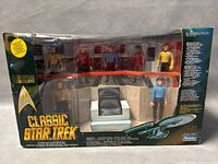 Front of the boxed set showing all Star Trek figures, bridge chair, and ship model inside clear window packaging
