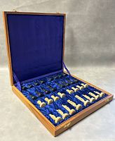 Wooden box opened showing the black and cream granite chess pieces neatly arranged on blue velvet lining inside the lid.