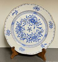 Full front view of the vintage Herend plate on a wooden stand with visible blue floral motif and lattice pattern.