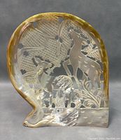 Front view of vintage mother of pearl carving showing deer and trees, highlighting natural iridescence and cutout details.