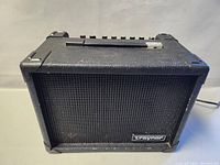 Front view of vintage Traynor guitar amplifier showing black metal grille with Traynor logo.
