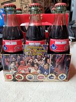 Front view of three 10oz Coca-Cola Classic glass bottles with special NHL team logos and hockey celebration artwork in original packaging.
