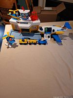 Full view of airport terminal, airplane, two helicopters, and fuel truck on table.