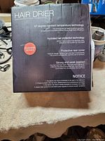 Box showing hair dryer features and branding with distressed packaging.