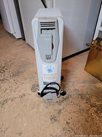 Front view of the oil filled heater showing control panel, power cord wrapped on base, and warning sticker.