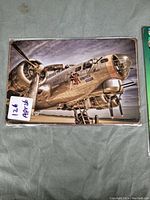 Metal sign showing the Memphis Bell aircraft with detailed metallic reflections on the plane, original wrapping visible.