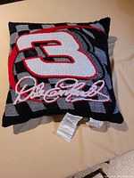 Front view of the square throw pillow featuring a prominent #3 and Dale Earnhardt's embroidered signature with checkered flag design.