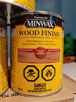 Close-up photo of one can of Minwax Premium Oil Wood Finish stain in Golden Pecan color showing label details and warnings.
