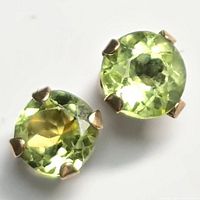 Close-up image of a single round peridot stud earring in 10kt gold prong setting, showing the light green color of the gemstone and gold claws.