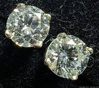 Pair of round diamond studs on black background showing setting detail