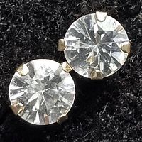 Close-up photo of one white sapphire earring showing gemstone cut and prong setting.