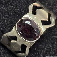 Close-up of oval faceted garnet gemstone set in cut-out sterling silver ring.