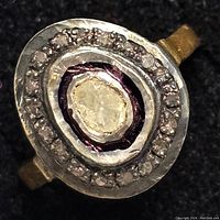 Close-up of the ring top showing the central rough diamond with surrounding smaller diamonds and ornamental border.