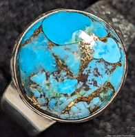 Close-up image of silver ring with round turquoise stone showing stone's vibrant blue color and matrix.