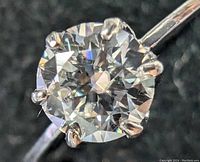 Close-up top view of round brilliant cut moissanite gemstone held by six prongs on white gold ring.