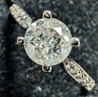 Close-up of center diamond and prong setting showing round brilliant diamond faceting and inclusion patterns