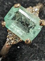 Close-up of emerald cut center stone and diamond accents on black background