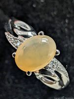 Close-up image of the 10kt gold ring with oval cabochon opal and side diamonds on a black background.