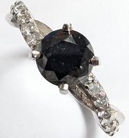 Close-up of round black diamond center and white diamond accented shoulders