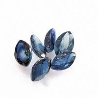 Six loose marquise cut blue sapphires arranged on a white surface.