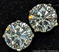 Close-up front view of two round brilliant cut diamonds set in 14K white gold four-prong setting on stud earrings.