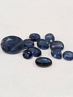 Group of eleven assorted blue sapphires laid on a white surface.