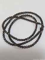 Top view of coiled silver beaded necklace showing bead texture and shine.