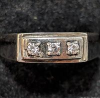 Close-up front view of silver ring showing three clear stones set in rectangular face.