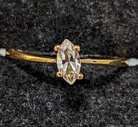 Close-up image showing the marquise-cut clear stone set on a thin silver band with some yellow discoloration